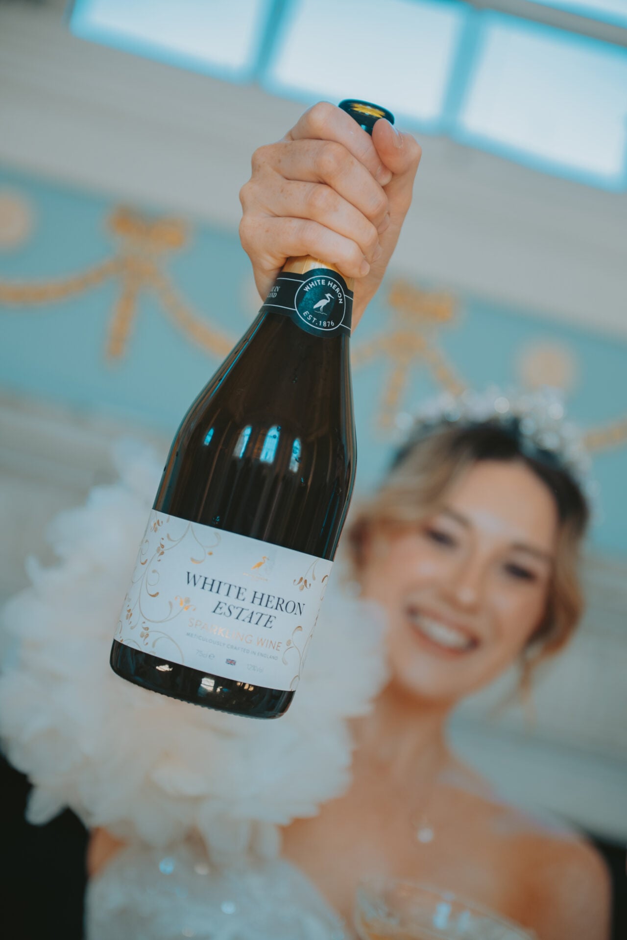 close up of White Heron Estate Sparkling being held aloft by bride